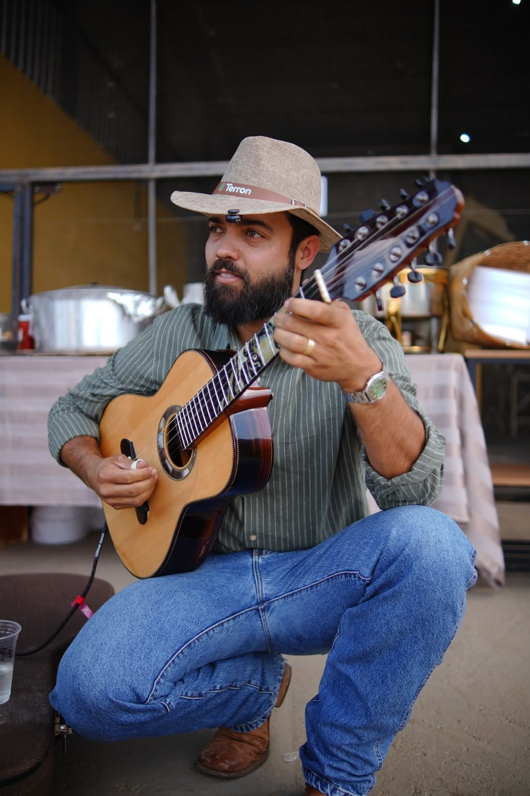 Lucas Reis, da Terron Nutrição Animal, tocando viola com o chapéu da marca